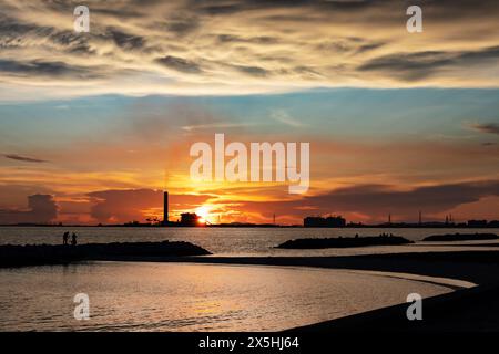 Die Verschmutzung wurde aus der Industriefabrik freigesetzt. Dass es auch viele Leute gibt, die wegen des wunderschönen Meeres und des Sonnenuntergangs einchecken. Stockfoto