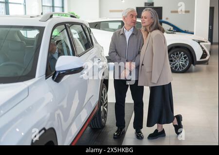 Ein älteres kaukasisches Paar wählt ein neues Auto in einem Autohändler. Stockfoto