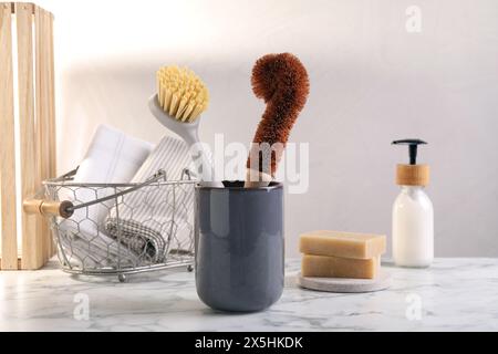 Bürsten im Halter und Reinigungswerkzeuge auf weißem Marmortisch Stockfoto