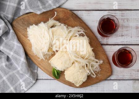 Östliche Süßigkeiten. Leckerer iranischer Paschmak und Tee auf weißem Holztisch, Blick von oben Stockfoto