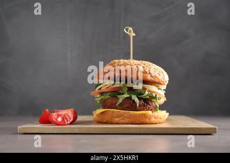 Gehen Sie mit köstlichem vegetarischen Burger auf grauem Tisch Stockfoto