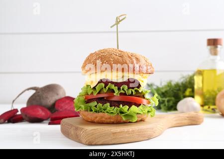 Köstlicher vegetarischer Burger und Zutaten auf weißem Holztisch Stockfoto