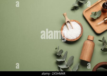 Aromatherapieprodukte. Flaschen mit ätherischem Öl, Meersalz und Eukalyptusblättern auf olivem Hintergrund, flache Lagen. Leerzeichen für Text Stockfoto