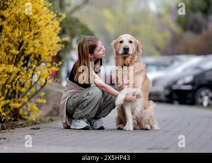 Mädchen Schlendert Mit Golden Retriever Im Frühling Die Straße Runter Stockfoto