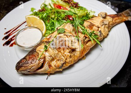 Forelle gebacken in cremiger Pilzsauce mit Salat und Kirschtomaten Stockfoto