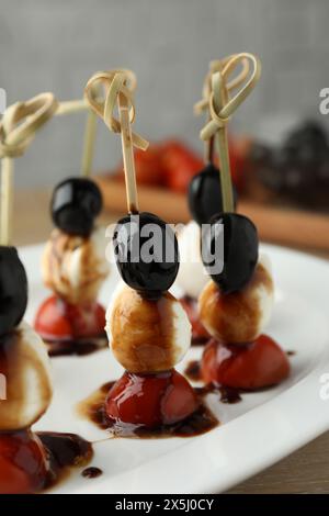 Leckere Canapes mit schwarzen Oliven, Mozzarella und Kirschtomaten auf dem Tisch, Nahaufnahme Stockfoto