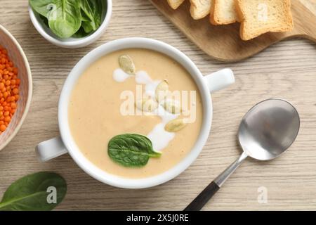 Gesunde Cremesuppe mit hohem Gehalt an pflanzlichen Fetten auf Holztisch serviert, flach gelegt Stockfoto