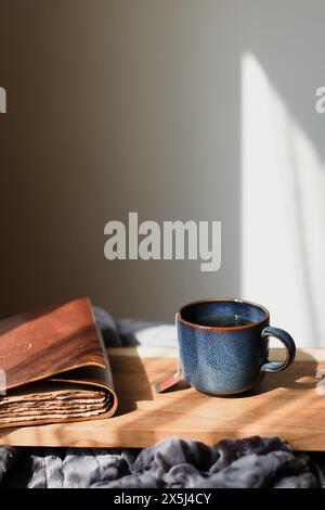 Morgenkaffee und Tagebuch auf einem Holztisch im Sonnenlicht Stockfoto