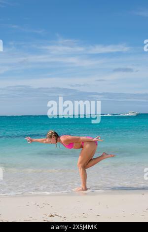 Eine blonde Frau macht Yoga in einem Bikini an einem Strand in der Karibik Stockfoto