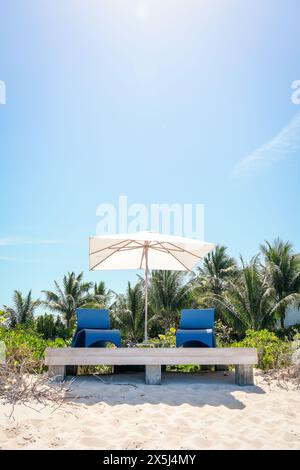 Zwei blaue Liegestühle und Sonnenschirm am Strand Stockfoto