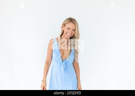 Frau in blauem Sommerkleid lächelnd mit weißem Hintergrund Stockfoto