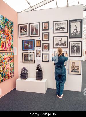 Frau arrangiert Bilderrahmen an der Wand auf der Kunstmesse. Stockfoto