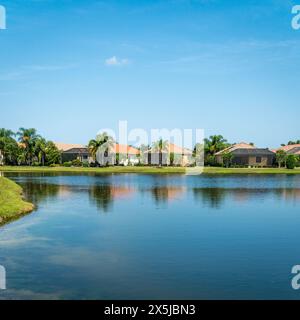 Lakewood Ranch, FL, USA-15. September 2022: Häuser am See in der oberen Mittelschicht mit Palmen und blauem Himmel. Stockfoto