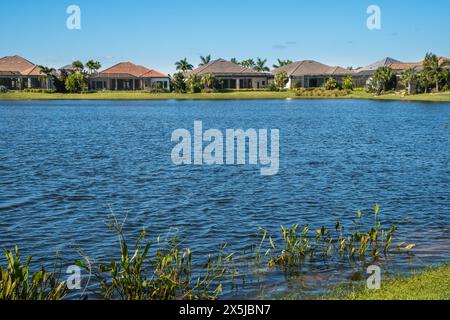 Lakewood Ranch, FL, USA-15. September 2022: Häuser am See in der oberen Mittelschicht mit Palmen und blauem Himmel. Stockfoto