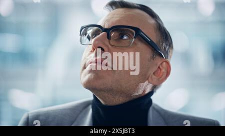 Porträt eines erfolgreichen kaukasischen Mannes mittleren Alters, der eine stilvolle Brille trägt und staunend aufblickt. Smart Executive. Digital Entrepreneur Thinking, Finden Von Lösungen. Abstrakter Kreativer Winkel Stockfoto