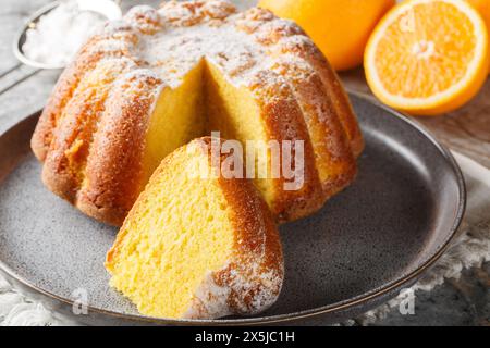 Feuchter Orangen-Pfund-Kuchen mit Orangenschale in Nahaufnahme auf einem Teller auf dem Tisch. Horizontal Stockfoto