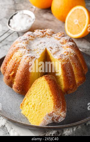 Traditioneller Vanillekuchen mit Orangensaft und Schale in Nahaufnahme auf einem Teller auf dem Tisch. Vertikal Stockfoto