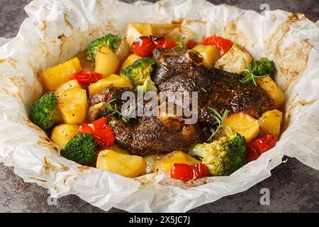 Gebackenes Lamm mit Kartoffeln, Brokkoli, Zwiebeln und Paprika in Pergament Nahaufnahme in einer Pfanne auf dem Tisch. Horizontal Stockfoto