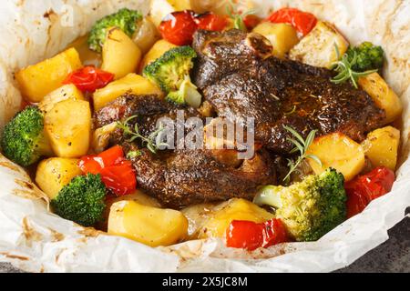 EN Papillote Lamm mit Kartoffeln, Brokkoli, Zwiebeln und Paprika in Pergament Nahaufnahme in einer Pfanne auf dem Tisch. Horizontal Stockfoto