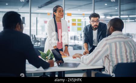 Multi-Ethnic Office Konferenzraum Geschäftsreisenden Meeting am Big Table. Ein vielfältiges Team kreativer Unternehmer spricht, nutzt Laptop. Spezialisten arbeiten in Digital e-Commerce Startup. Stockfoto