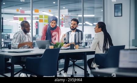 Diversity Modern Office: Motivierte muslimische Geschäftsfrau im Hijab führt Meetings, verwendet Laptop, spricht über Unternehmenswachstum, Brainstorming mit Kollegen. Digitale Unternehmer arbeiten am E-Commerce-Projekt Stockfoto