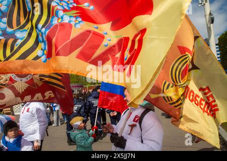 Moskau, Russland. Mai 2024. Die Menschen halten Fahnen während einer feierlichen Parade, die zum Siegtag der russischen Expo anlässlich der internationalen Ausstellung und des Forums im VDNKh-Ausstellungszentrum in Moskau, Russland, markiert ist. Russland feiert 79 Jahre seit dem Sieg über Nazi-Deutschland im Zweiten Weltkrieg Stockfoto