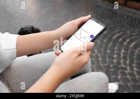 Frau hat draußen eine Nachricht auf dem Handy empfangen, Nahaufnahme. Abbildung des Umschlags auf dem Gerätebildschirm Stockfoto