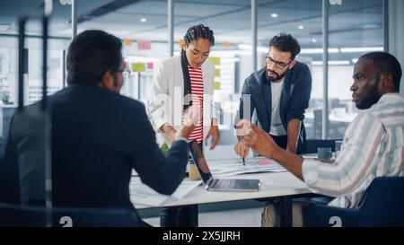 Multi-Ethnic Office Konferenzraum Geschäftsreisenden Meeting am Big Table. Ein vielfältiges Team kreativer Unternehmer spricht, nutzt Laptop. Spezialisten arbeiten in Digital e-Commerce Startup. Stockfoto