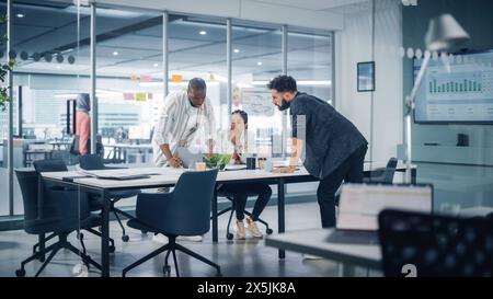 Multi-Ethnic Office Conference Room Meeting: Drei-köpfige Creative Entrepreneurs sprechen über Wachstumsstrategie. Stilvolle junge Geschäftsleute arbeiten an Digital e-Commerce Startup. Stockfoto
