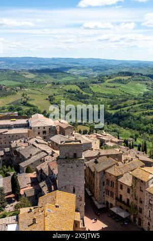 Ein wunderschöner Blick über die Dächer und Türme von San Gimignano in der Toskana, Italien, mit sanften grünen Hügeln und Feldern im Hintergrund an einem sonnigen Tag Stockfoto