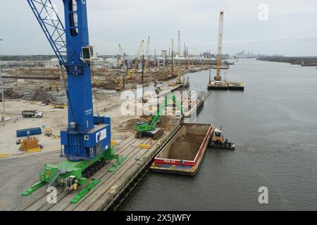 Schlepper mit Lastkahn, blauem Mobilkran und anderen schweren Industriemaschinen, die in einem neuen Containerterminal im Bau am Fluss Savannah eingesetzt werden. Stockfoto