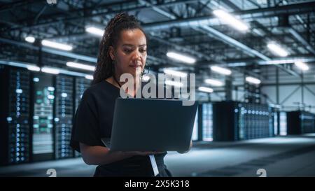 Porträt einer erfolgreichen Chefingenieurin oder CEO, die einen Laptop zur Optimierung der Big Server Farm Cloud Computing Facility im Evening Office nutzt. Cyber Security, Network Protection Concept Stockfoto