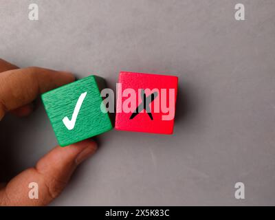 Draufsicht Hand hält farbigen Block mit dem Symbol rechts und falsch auf grauem Hintergrund. Stockfoto