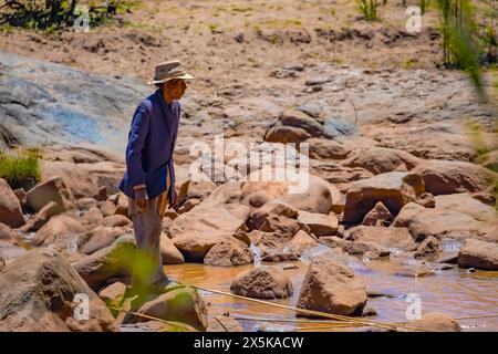 Antananarivo, Madagaskar 07. Oktober 2023. Ein älterer Mann fängt Fische für seine Tochter in einem kleinen Bach Stockfoto