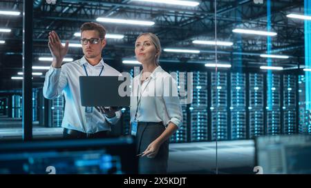 Im Rechenzentrum: Geschäftspartner sprechen, schauen und Brainstorming im Abendbüro, während sie am Laptop arbeiten. People arbeitet mit Cloud Infrastructure Concept Stockfoto