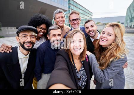 Eine Gruppe multirassischer Geschäftsleute, die zusammen ein Selfie machen und die Kamera lächelnd betrachten. Stockfoto