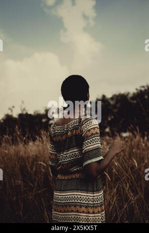 Nigeria, Bundesstaat Delta, Rückansicht einer Frau in gemustertem Kleid, die auf dem Feld steht Stockfoto