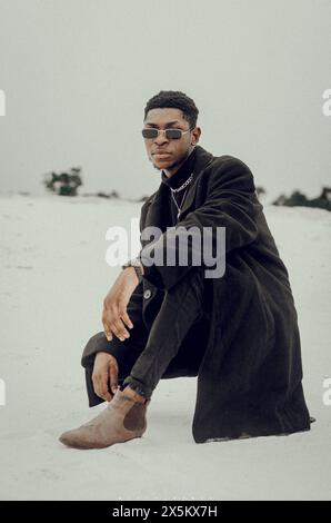 Nigeria, Delta State, Porträt eines schicken Mannes, der auf Sand sitzt Stockfoto