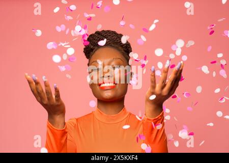 Studio-Aufnahme einer stilvollen Frau mit fallendem Konfetti Stockfoto