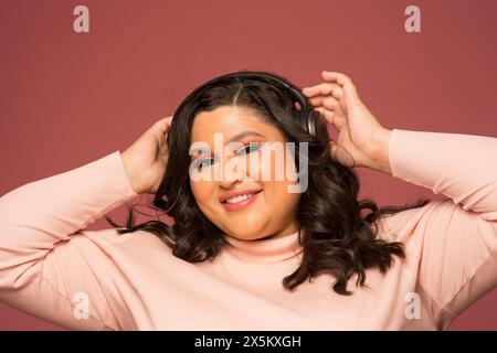 Studio-Porträt einer lächelnden Frau mit Kopfhörern Stockfoto