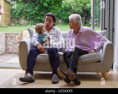 Vater mit Sohn und Großvater sitzen auf dem Sofa Stockfoto