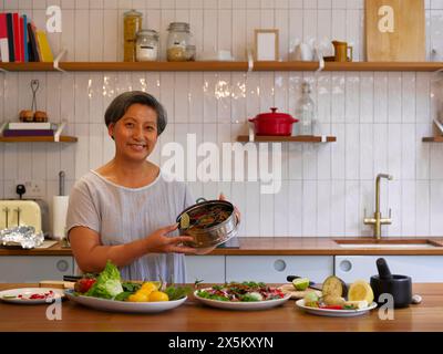 Porträt einer Frau, die frisch zubereitetes Essen in der Küche zeigt Stockfoto