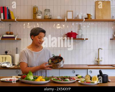 Porträt einer Frau, die frisch zubereitetes Essen in der Küche zeigt Stockfoto