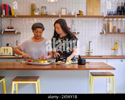 Mutter und Erwachsene Tochter schneiden Gemüse in der Küche Stockfoto