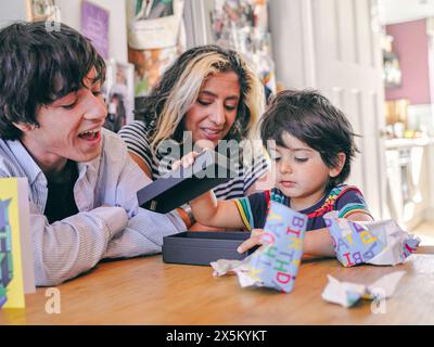 Junge Eröffnung Geburtstagsgeschenk mit Familie Stockfoto