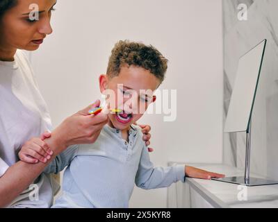 Mutter hilft dem Sohn beim Zähneputzen im Badezimmer Stockfoto