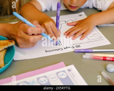 Nahaufnahme einer Mutter, die dem Sohn bei Hausaufgaben hilft Stockfoto