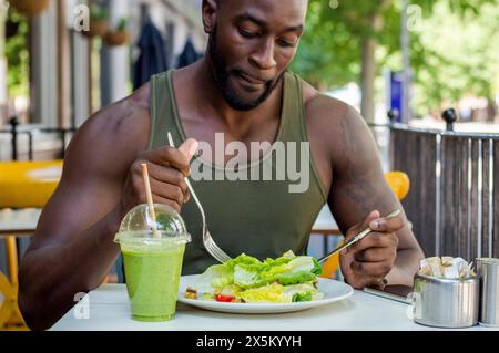 Mittelgroßer Mann, der Salat im Café isst Stockfoto