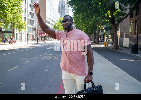 Mann mit Aktentasche, der auf der Straße steht und für den Transport winkt Stockfoto