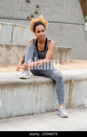 Frau, die vor dem Training Schnürsenkel in Sportschuhen bindet Stockfoto